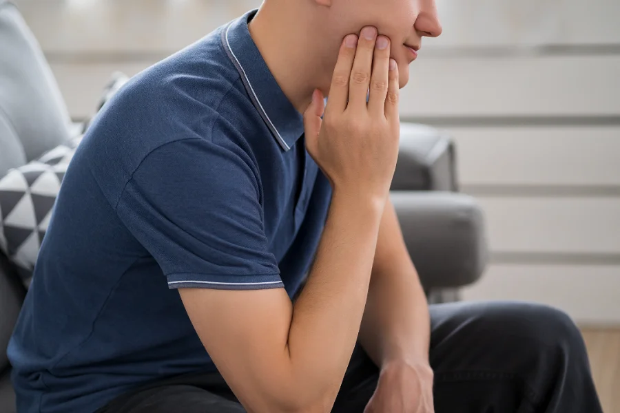 A person sitting and holding his chin with one hand