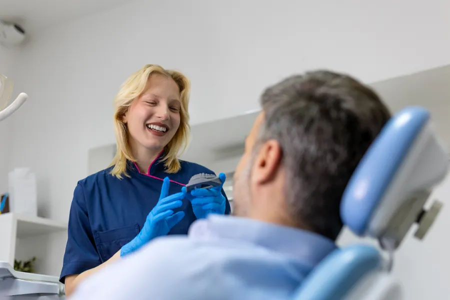 A woman smiling at a man in a dental chair