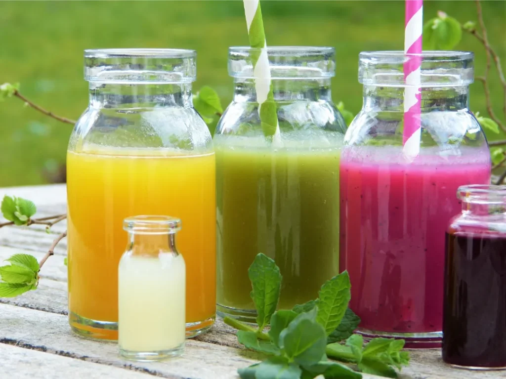 Three glass bottles with colorful juices and straws