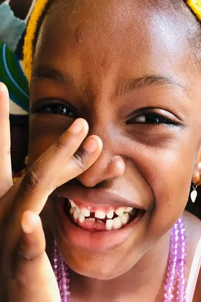 Young girl smiling brightly and holding her nose with her fingers