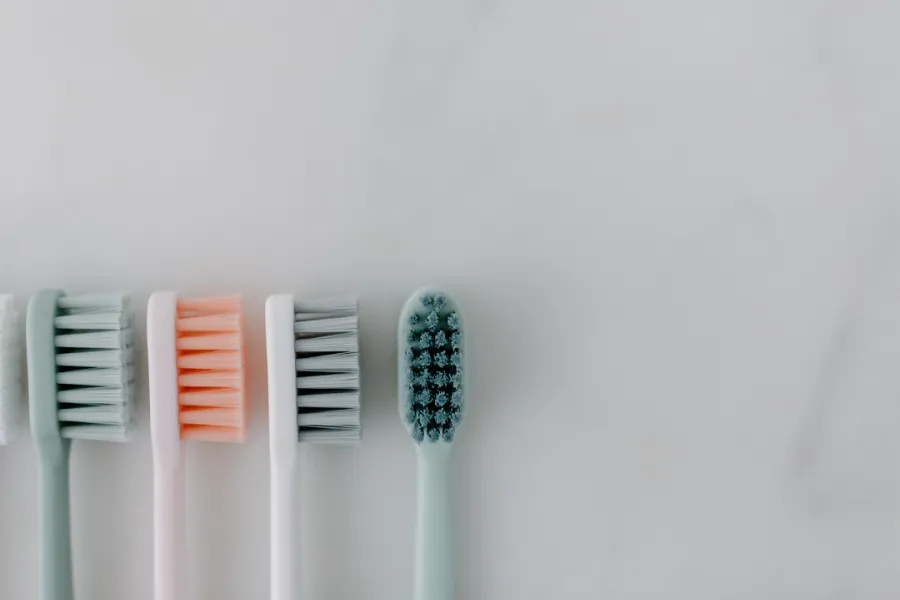 Four toothbrush heads with different colored bristles are aligned vertically against a white background